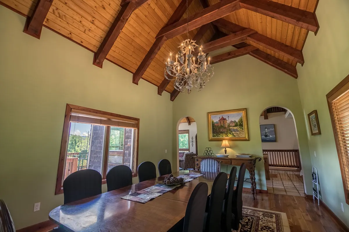 A formal dining area with a central dining table beneath an elegant chandelier, flanked by large windows and artwork on the wall. The setup is perfect for memorable family dinners, celebratory feasts, or cozy holiday gatherings, capturing the spirit of togetherness and shared meals described in the section.