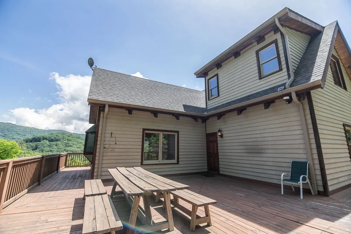 The exterior deck area features a picnic table with the house in the background and a sweeping mountain view. The space is ideal for group meals, outdoor celebrations, and relaxing with friends while taking in the scenery.